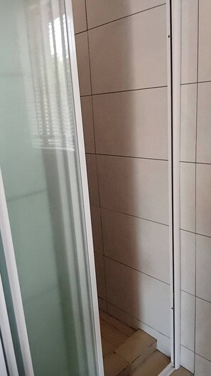 A corner of a room with a tiled floor and a glass door.