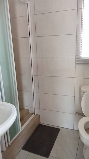 Ein Badezimmer mit Dusche, Toilette und Waschbecken.