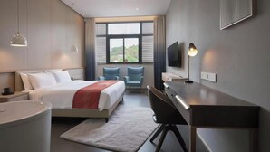 A modern hotel room with a bed, desk, chairs, a TV, and a large window with a view. - Nanxianglou Art Hotel (Shenzhen)