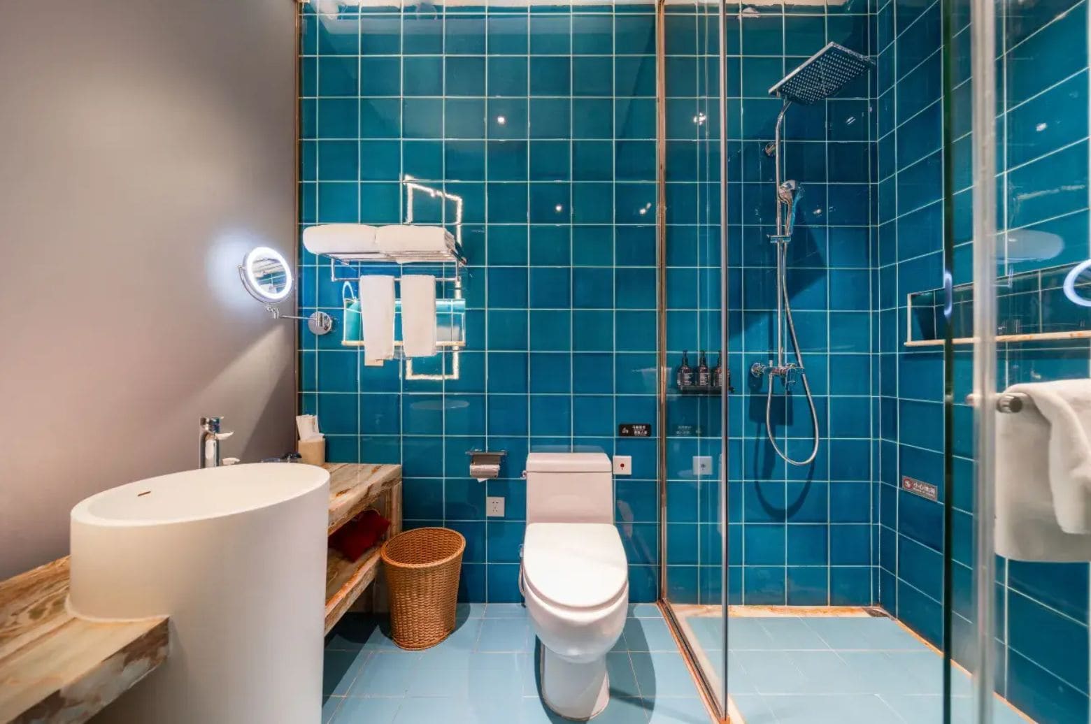 A modern bathroom with a glass-enclosed shower, a white toilet, and a large white sink.