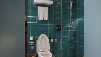 A bathroom with a toilet, a shower, and a glass partition.