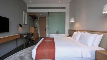 A hotel room with a bed, a desk, a TV, a bathroom, and a wardrobe.