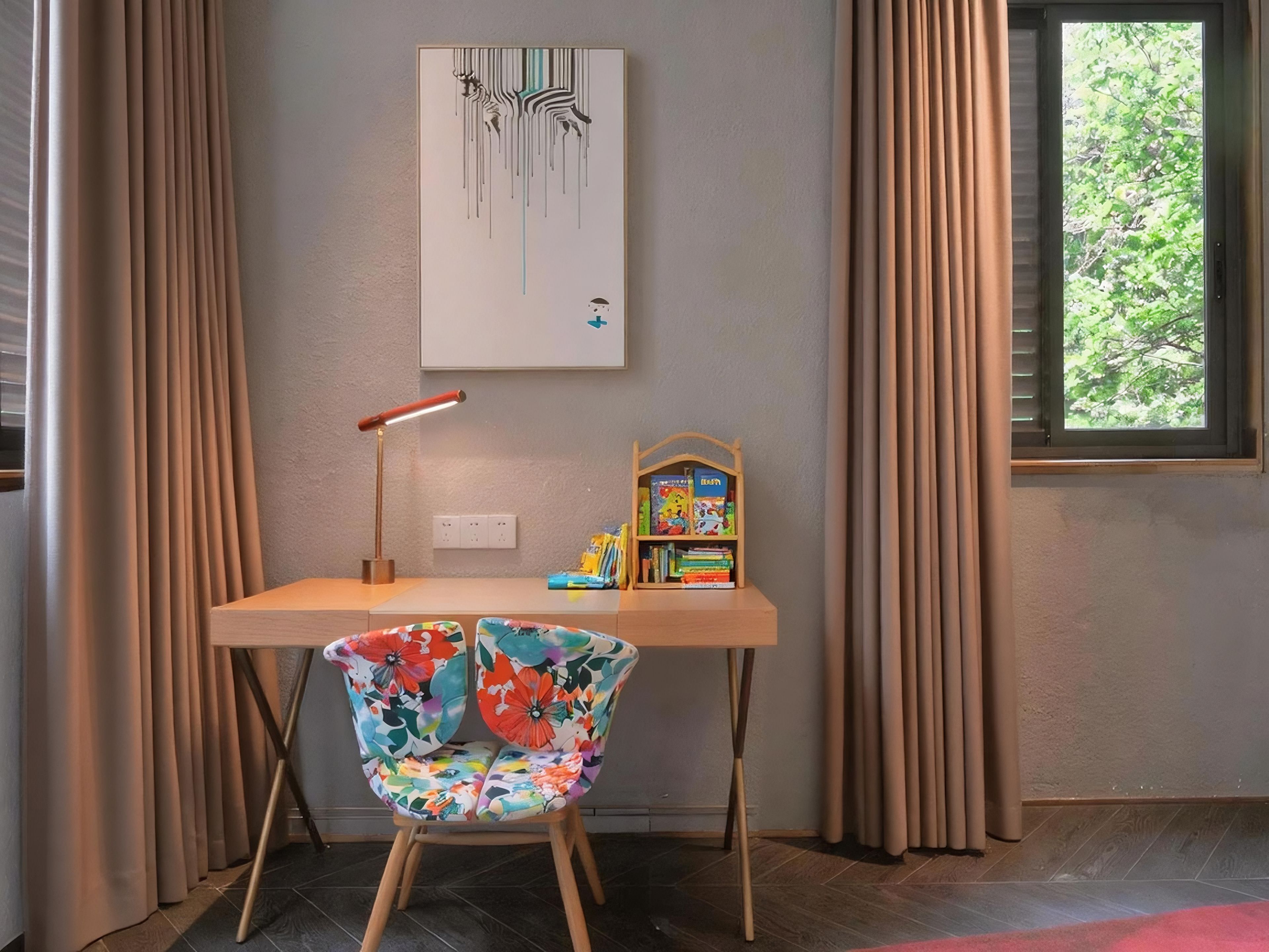A room with a desk, a chair, a lamp, a bookshelf, and a window with curtains.