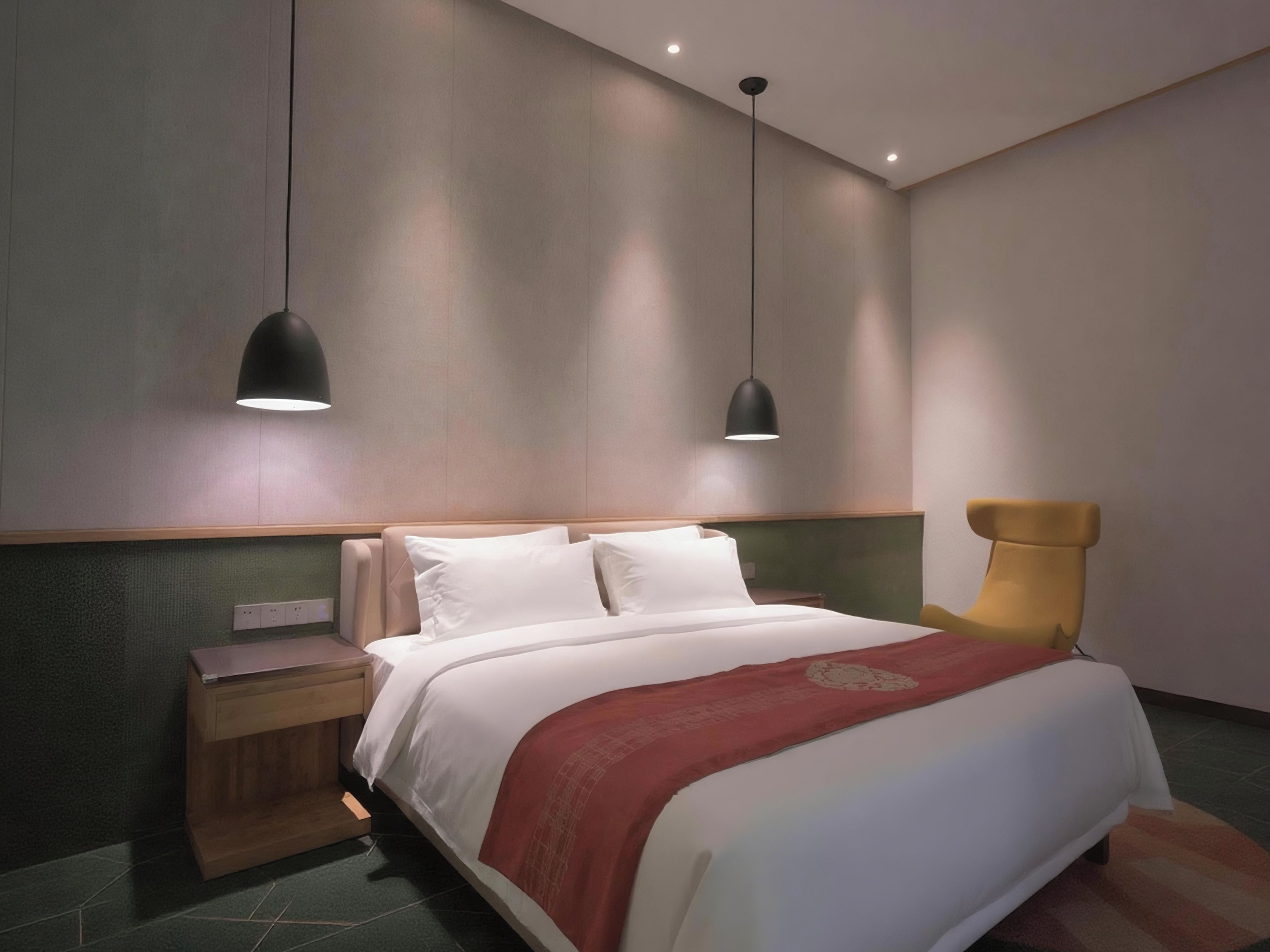 Habitación de hotel moderna con una cama grande, mesitas de noche y una sola silla.