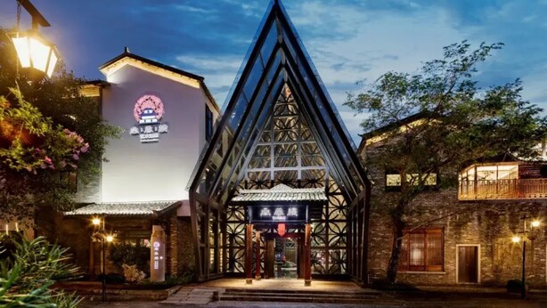 A traditional building with a prominent triangular glass structure and a sign with Chinese characters. - Nanxianglou Art Hotel (Shenzhen)