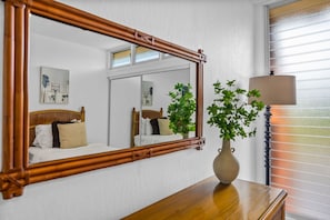 A room with a bed, a mirror, a vase with a plant, and a lamp. - Beachfront 2BD Unobstructed Ocean Views - Kulakane 304 (Napili-Honokowai)