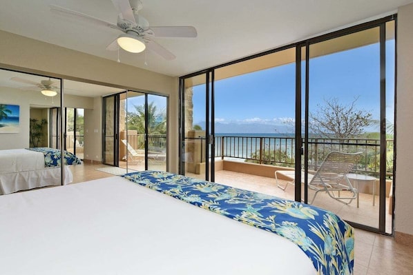 A bedroom with a large bed, a balcony with a view of the ocean, and a ceiling fan. - Beachfront 2BD w Stunning Ocean View-paki Maui 424 (Kaanapali)