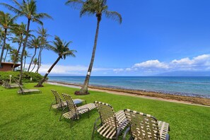 A beachside lounge with palm trees and chairs facing the ocean. - Beachfront 2BD w Stunning Ocean View-paki Maui 424 (Kaanapali)
