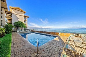A swimming pool with lounge chairs, a view of the ocean, and a building with balconies. - 2BD Oceanfront Condo With Pool Near Beach-nohonani 105 (Napili-Honokowai)