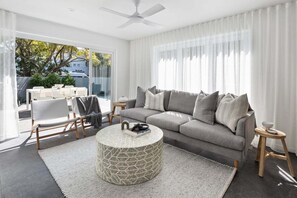 A modern living room with a grey sofa, a round coffee table, and a ceiling fan. - The Riverside Wander, Noosaville (Noosaville)