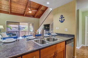 A kitchen with a granite countertop, stainless steel sink, wooden cabinets, and a ceiling fan. - Family Getaway 2BD w AC Pool Beach - Kihei Resort 202 (Kihei)