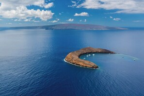 An aerial view of a crescent-shaped island with clear blue waters and a distant mountain range. - Family Getaway 2BD w AC Pool Beach - Kihei Resort 202 (Kihei)