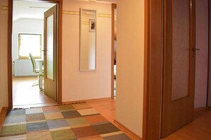 Ein Flur mit Schachbrettmuster-Teppich, Holztüren und einem Heizkörper.