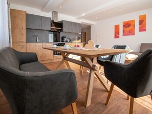 A modern kitchen with wooden cabinets, a dining table, and black chairs. - Studio - Eiblhof, Austria (Schladming)