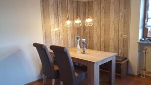 A dining area with a wooden table and chairs, pendant lights, and a rustic wall. - Apartment in Bodenmais near Grosser Arber (Bodenmais)