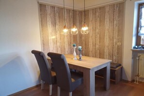 Een eetgedeelte met een houten tafel en stoelen, hanglampen en een rustieke wand.
