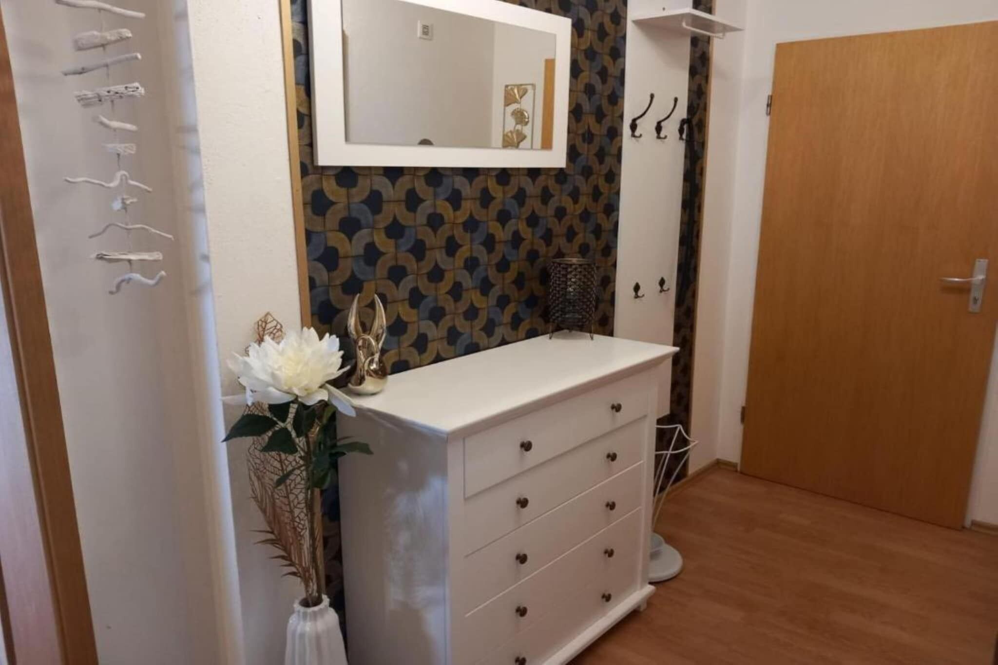 Ein Badezimmer mit einem weißen Waschtisch, einem Spiegel, einer Zierpflanze und einer Wand mit Muster.