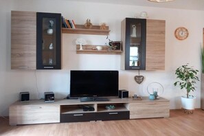 Un salon moderne avec un téléviseur à écran plat, des meubles en bois et une plante en pot.