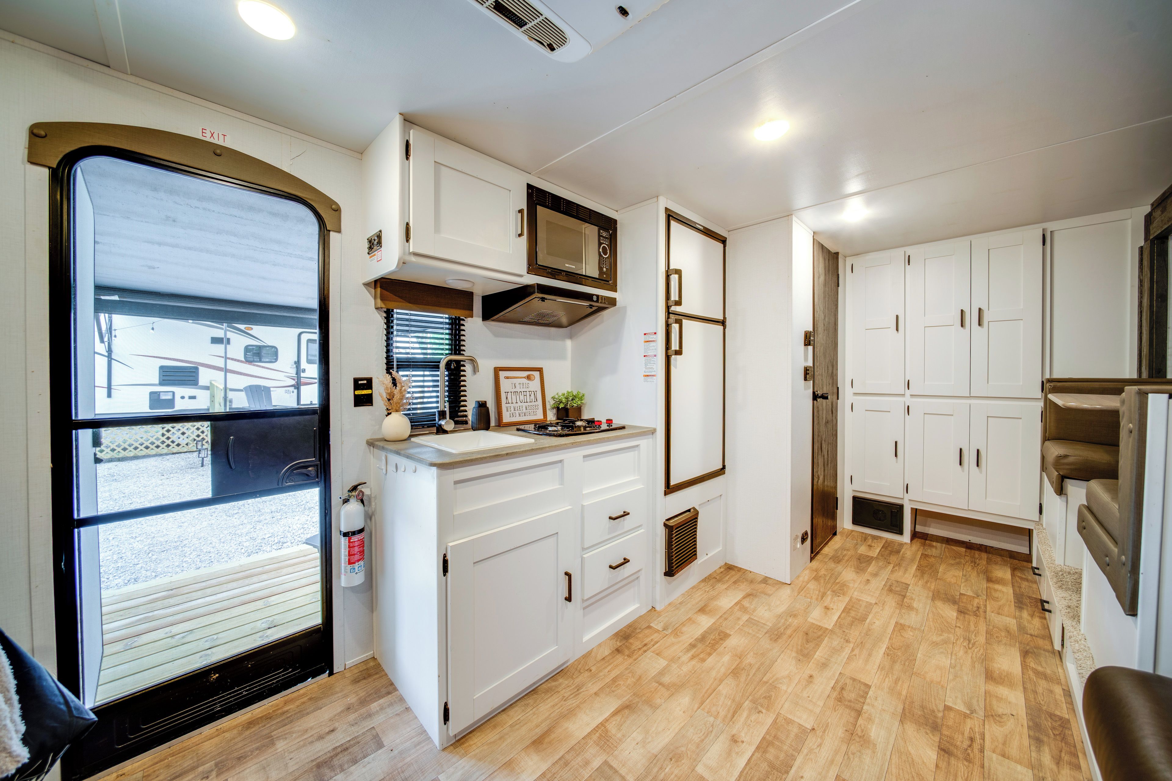 A compact kitchen with white cabinetry, a microwave, and a sink.