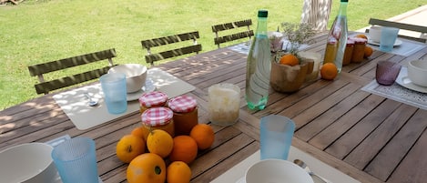 An outdoor dining table set with chairs, a variety of food items, and beverages.