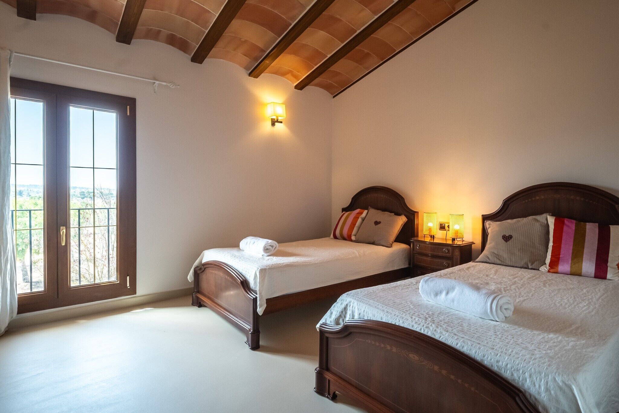 A bedroom with two beds, a balcony door, and a wall-mounted light fixture.