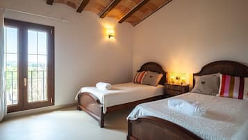 A bedroom with two beds, a balcony door, and a wall-mounted light fixture.