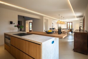 A modern kitchen with a central island, a dining area with a pool table, and a living space with a sofa and coffee table. - Villa Na Maria: renovated finca in Porreres with private pool (Porreres)