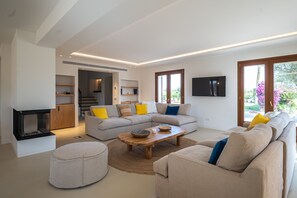 Ein modernes Wohnzimmer mit einer Sofagarnitur, einem Couchtisch und einem Flachbildfernseher.