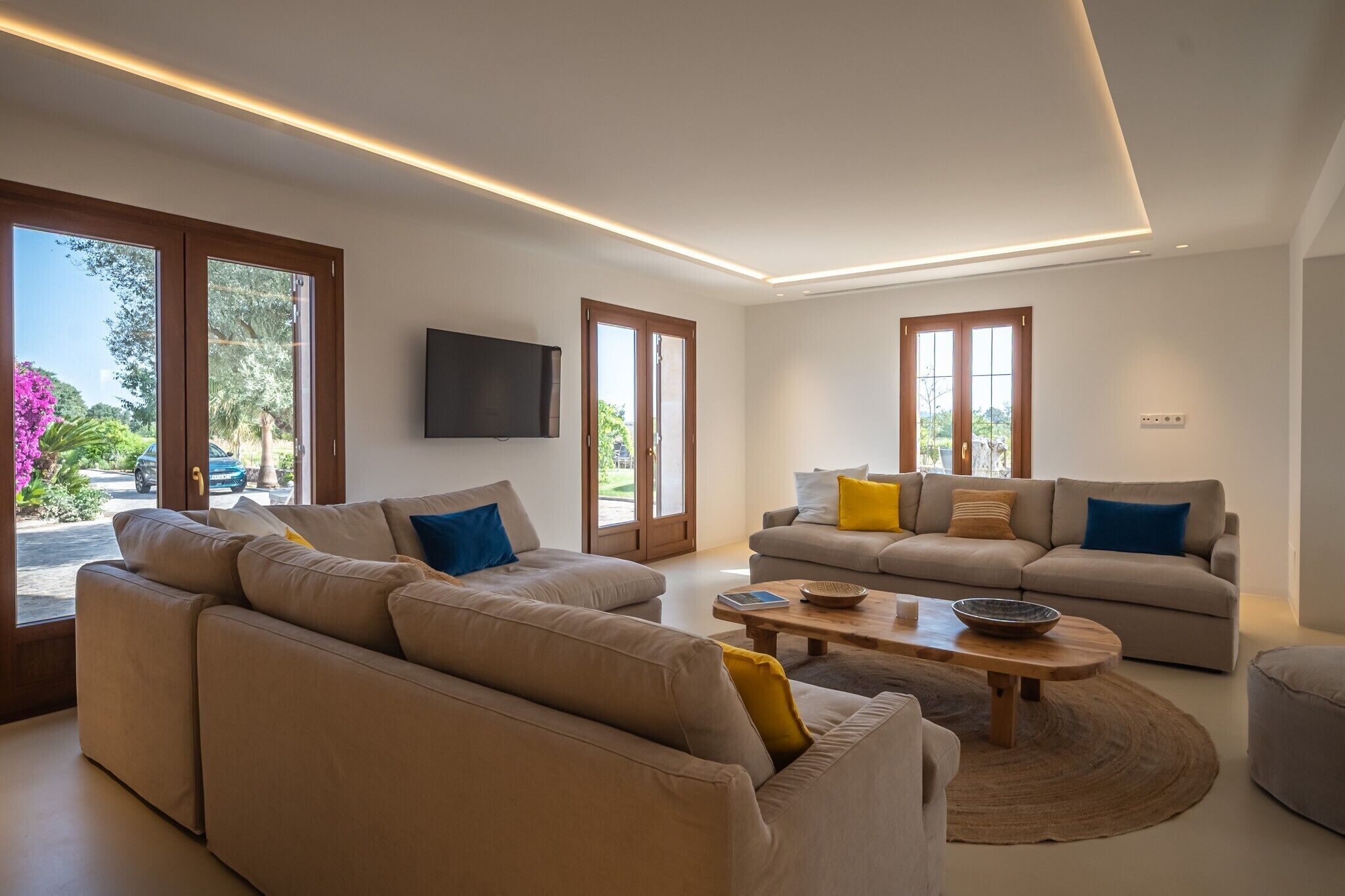 Ein modernes Wohnzimmer mit zwei Sofas, einem Couchtisch und einem an der Wand montierten Fernseher.