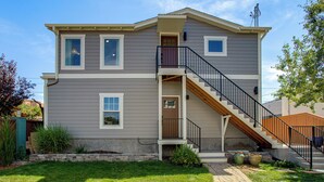 A two-story house with a front porch, a staircase, and a small garden area. - Mountain & Lake Views! Unit 1 Mi to Empower Field (Denver)