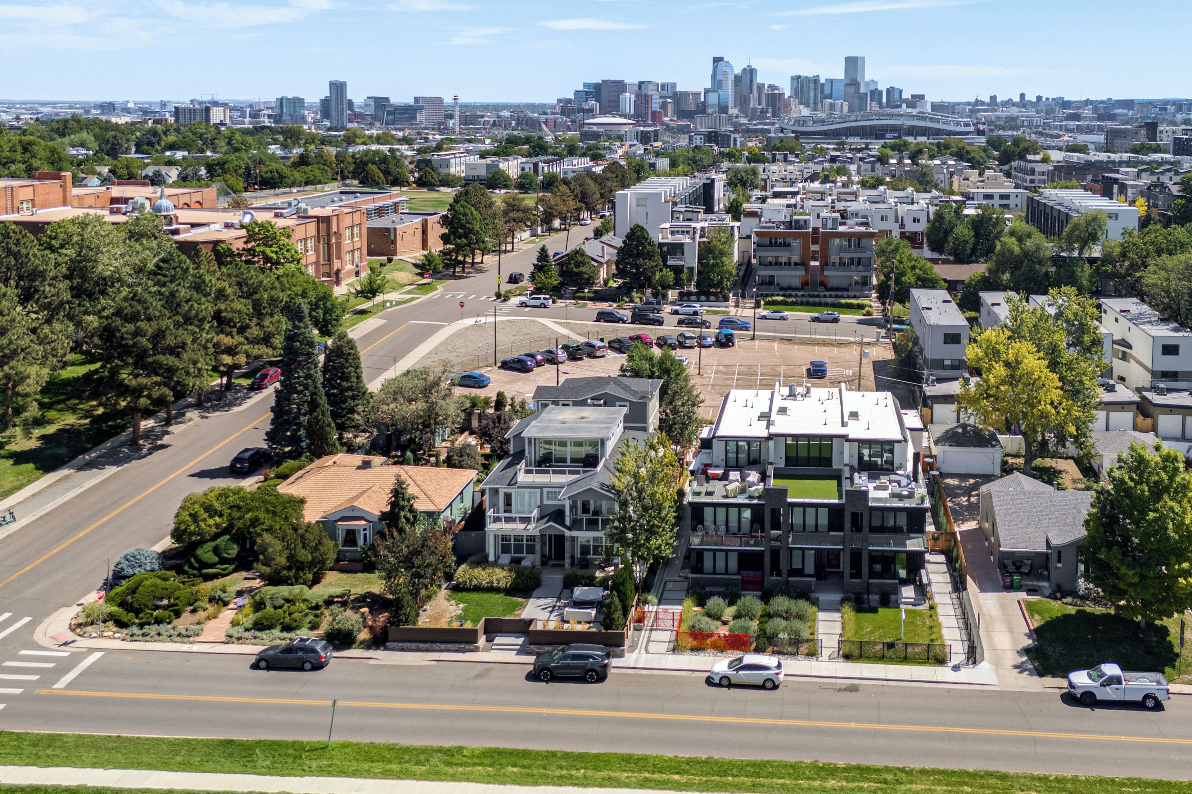A residential area with modern houses, a main road, and a distant city skyline.