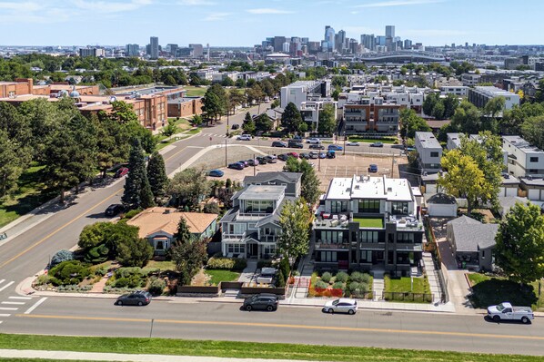 A residential area with modern houses, a main road, and a distant city skyline. - Mountain & Lake Views! Unit 1 Mi to Empower Field (Denver)