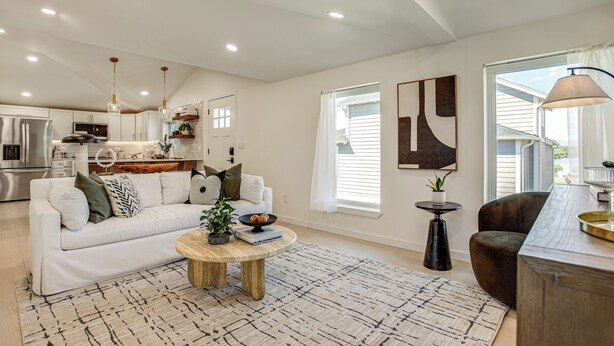 A spacious living area with a white sofa, a coffee table, and a dining area with a kitchen in the background. - Mountain & Lake Views! Unit 1 Mi to Empower Field (Denver)
