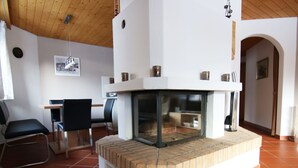 Ein Wohnzimmer mit Kamin, Essbereich und einer Sitzecke mit Sesseln.