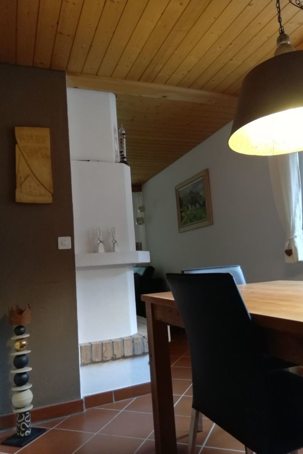 Een keuken met een houten plafond, een witte koelkast en een eettafel met stoelen.