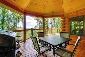 Eine überdachte Terrasse im Freien mit Grill, Stühlen und Tisch.