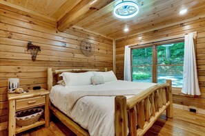 Ein Schlafzimmer einer Holzhütte mit Bett, Nachttisch und Fenster.