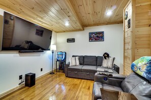 A cozy living room with a wooden ceiling, a gray sofa, a leather armchair, a flat-screen TV, and a gaming console. - Mtn Views, Hot Tub, & Theater! Sevierville Gem (Sevierville)
