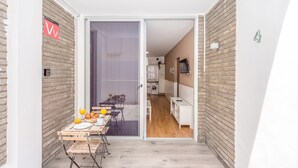Un couloir étroit mène à une salle à manger où une table est dressée pour deux personnes. On y trouve également un lave-linge et un téléviseur fixé au mur.