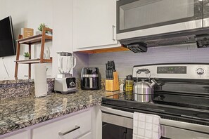 A kitchen with a granite countertop, a built-in oven, a microwave, a coffee maker, and a kettle. - New 6BR Two Unit - Perfect for Large Groups (Indianapolis)