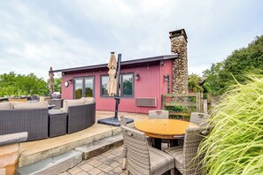 A red building with a stone chimney, outdoor seating with wicker furniture, and a wooden fence. - 6,000-Sq-Ft Estate in Delaware River Valley (Milford)