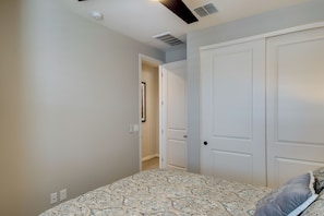 A bedroom with a patterned bedspread, a white door, and a hallway leading to another room. - Steps to Pool & Park! San Tan-Area Family Getaway (Gilbert)