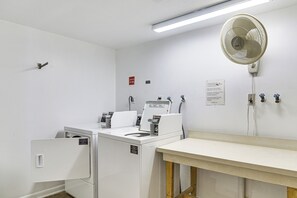 A laundry room with two washers and dryers, a fan, and a table. - 1 Block to Beach! Indian Shores Condo, Pool Access (Indian Shores)