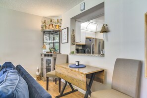 A compact living space with a kitchenette, a dining area with a wooden table and bench, and a seating area with a sofa. - 1 Block to Beach! Indian Shores Condo, Pool Access (Indian Shores)