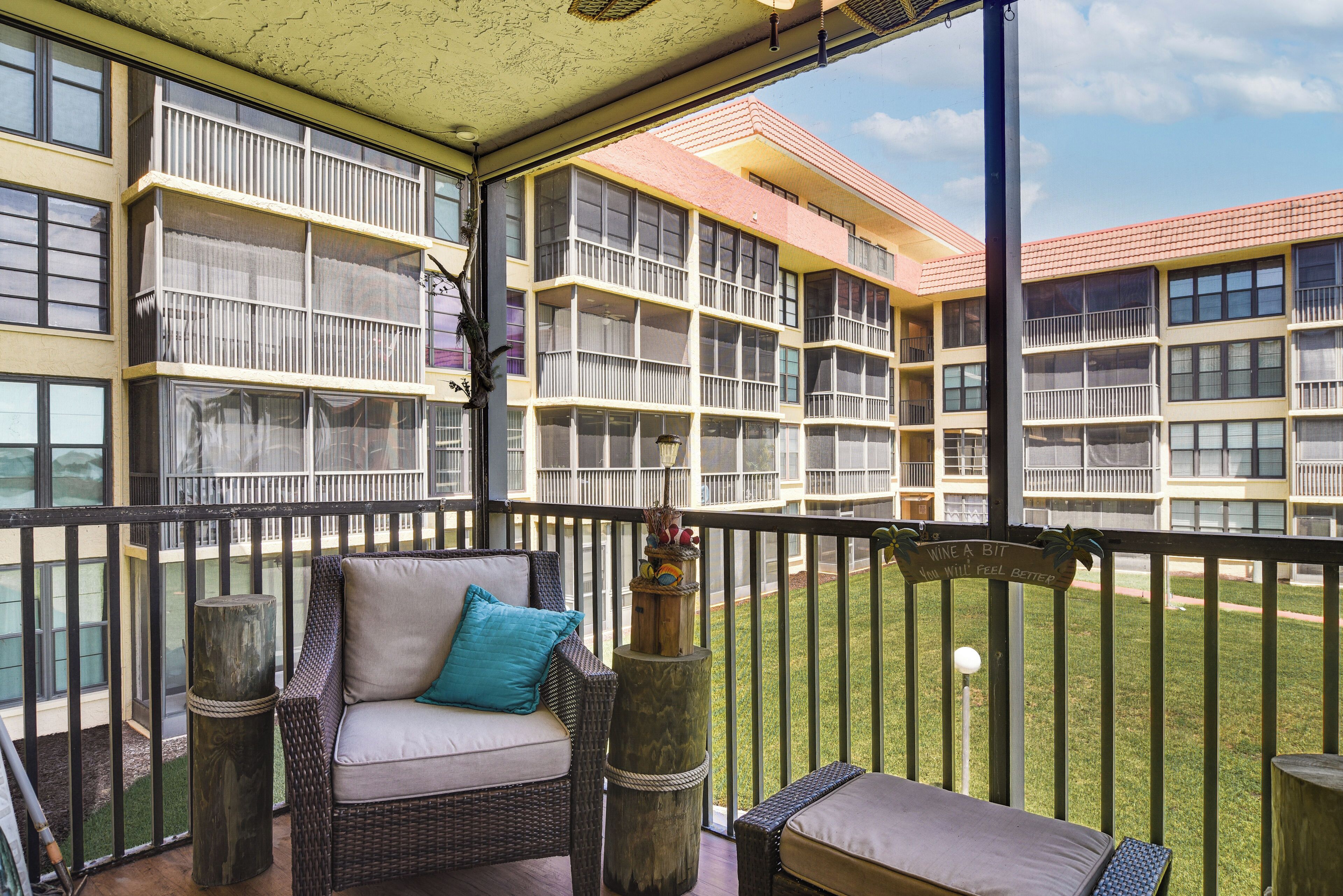 Een balkon met rieten meubels, een tafeltje en een decoratieve plant.