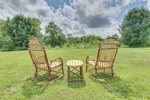 Two rocking chairs and a small table in a grassy field with trees in the background. - 1 Mi to Oakland City University: Modern Apt (Oakland City)