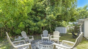 En baghave med bålsted og fire Adirondack-stole.
