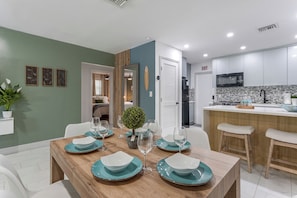 A modern kitchen with white cabinets, a built-in microwave, and a tiled backsplash.