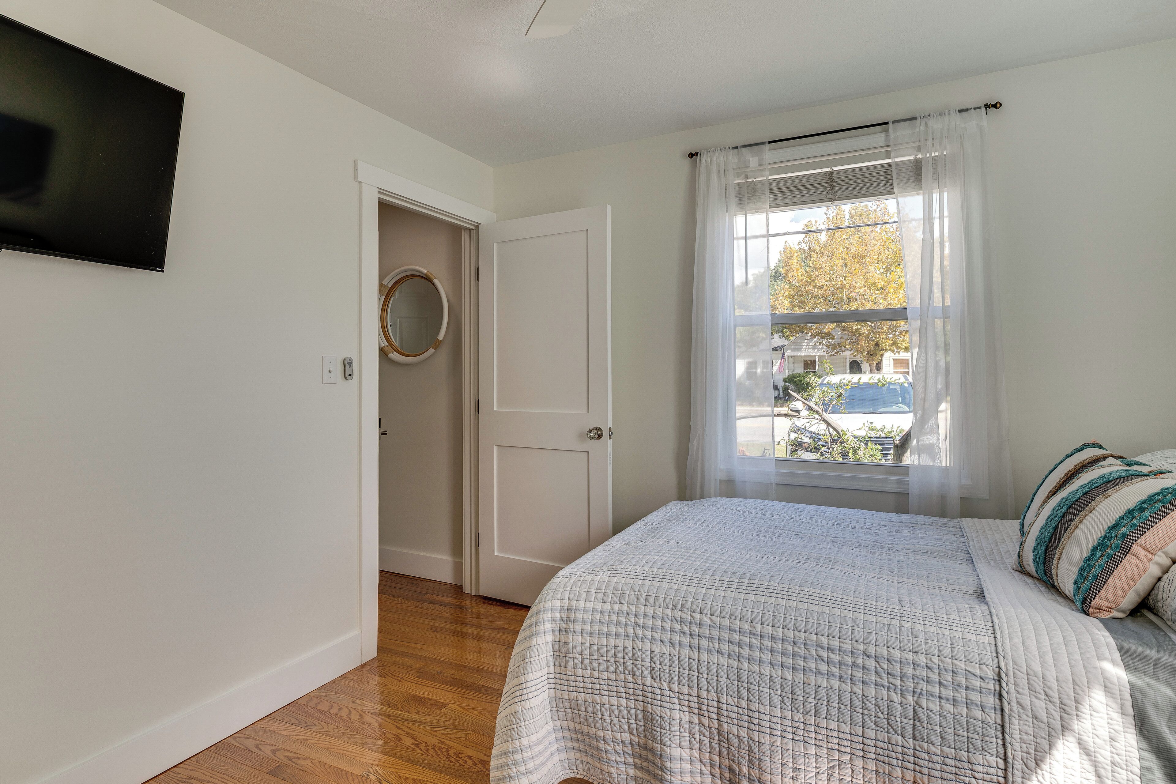 A bedroom with a bed, a door leading to a bathroom, and a window with curtains.