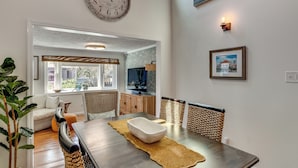 Een eethoek met een houten tafel, stoelen en een grote wandklok.